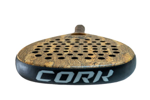 Close-up of a Cork Padel Premium Hybrid III Racket showcasing its cork-textured surface and advanced anti-vibration cap, with a multi-diameter hole pattern. CORK is prominently displayed on the side in large white letters against a plain white background.